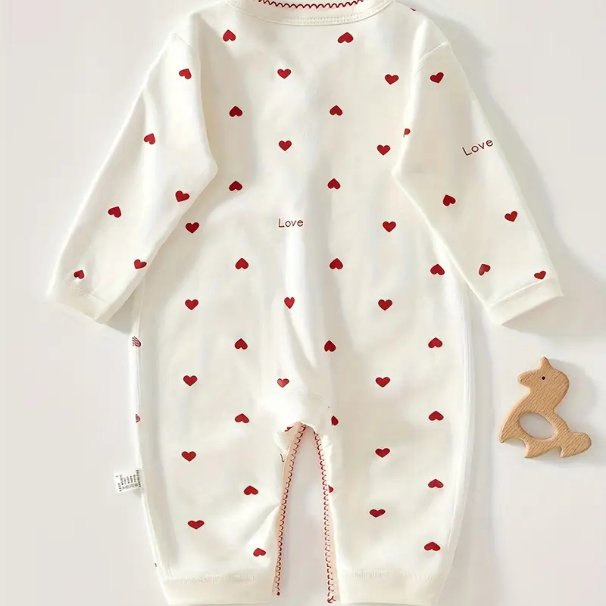 Back view of newborn one-piece with red heart print and “love” detail