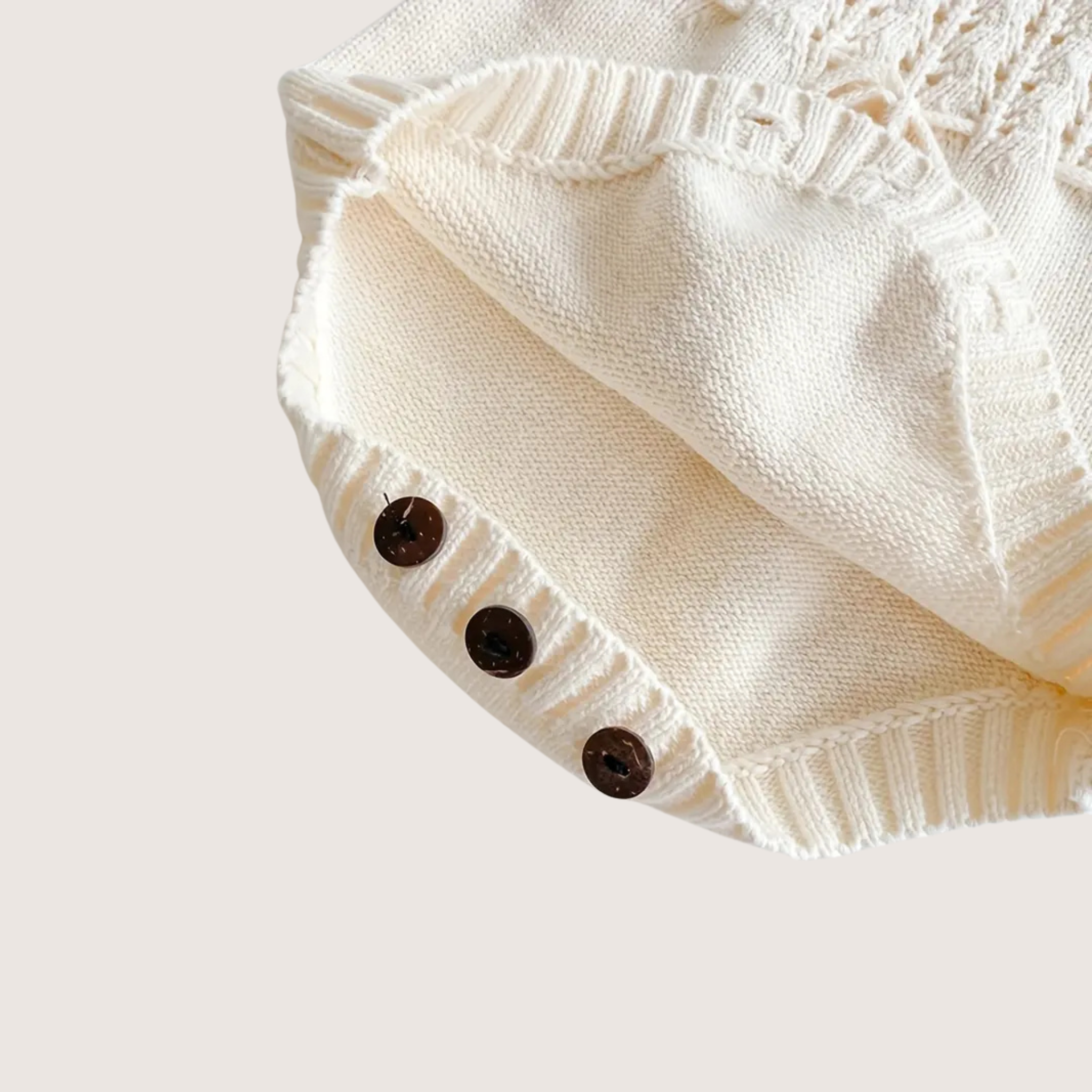 Knit baby jumpsuit with wooden buttons and adjustable straps